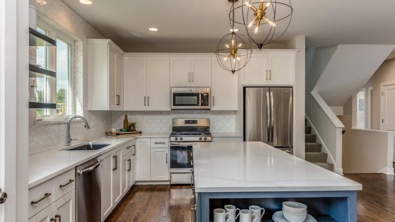 Kitchen with a large island, custom cabinets, granite countertops, and stainless-steel appliances.